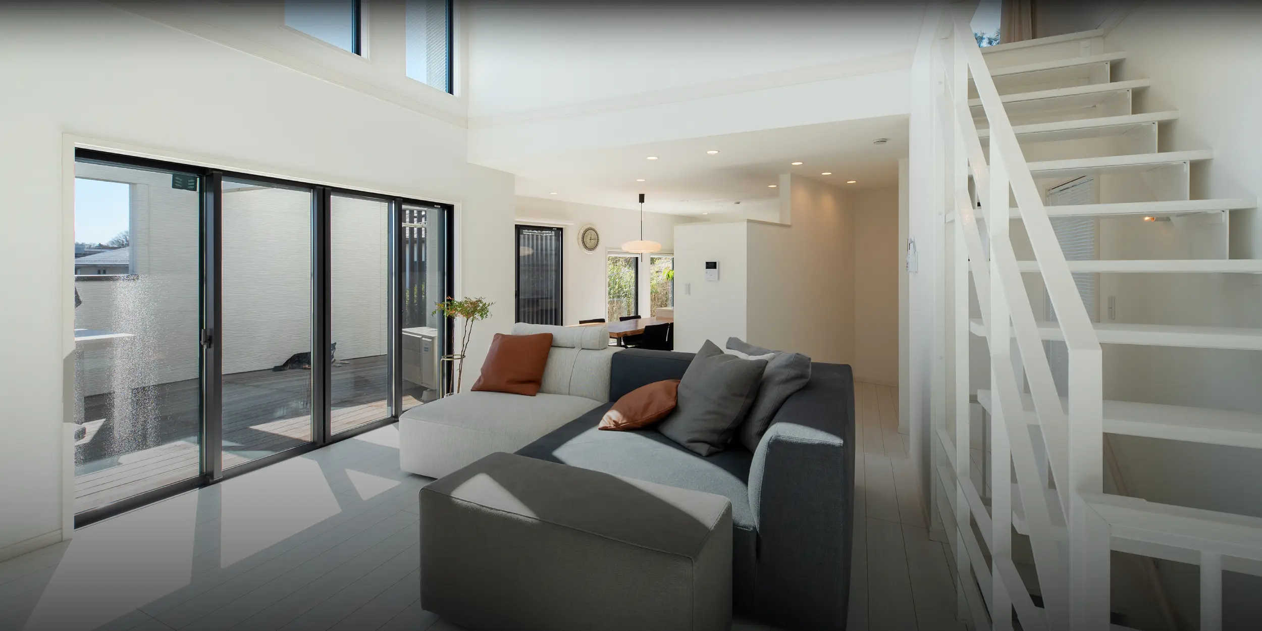 横浜の工務店が提案する開放的なリビング：吹き抜けと大きな窓、白い階段がある空間