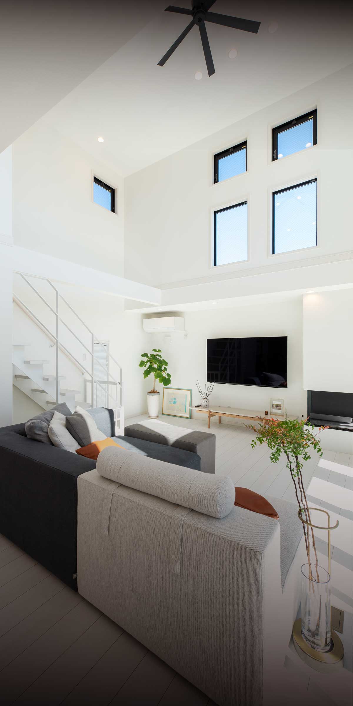 横浜の工務店が提案する開放的なリビング：吹き抜けと大きな窓、白い階段がある空間