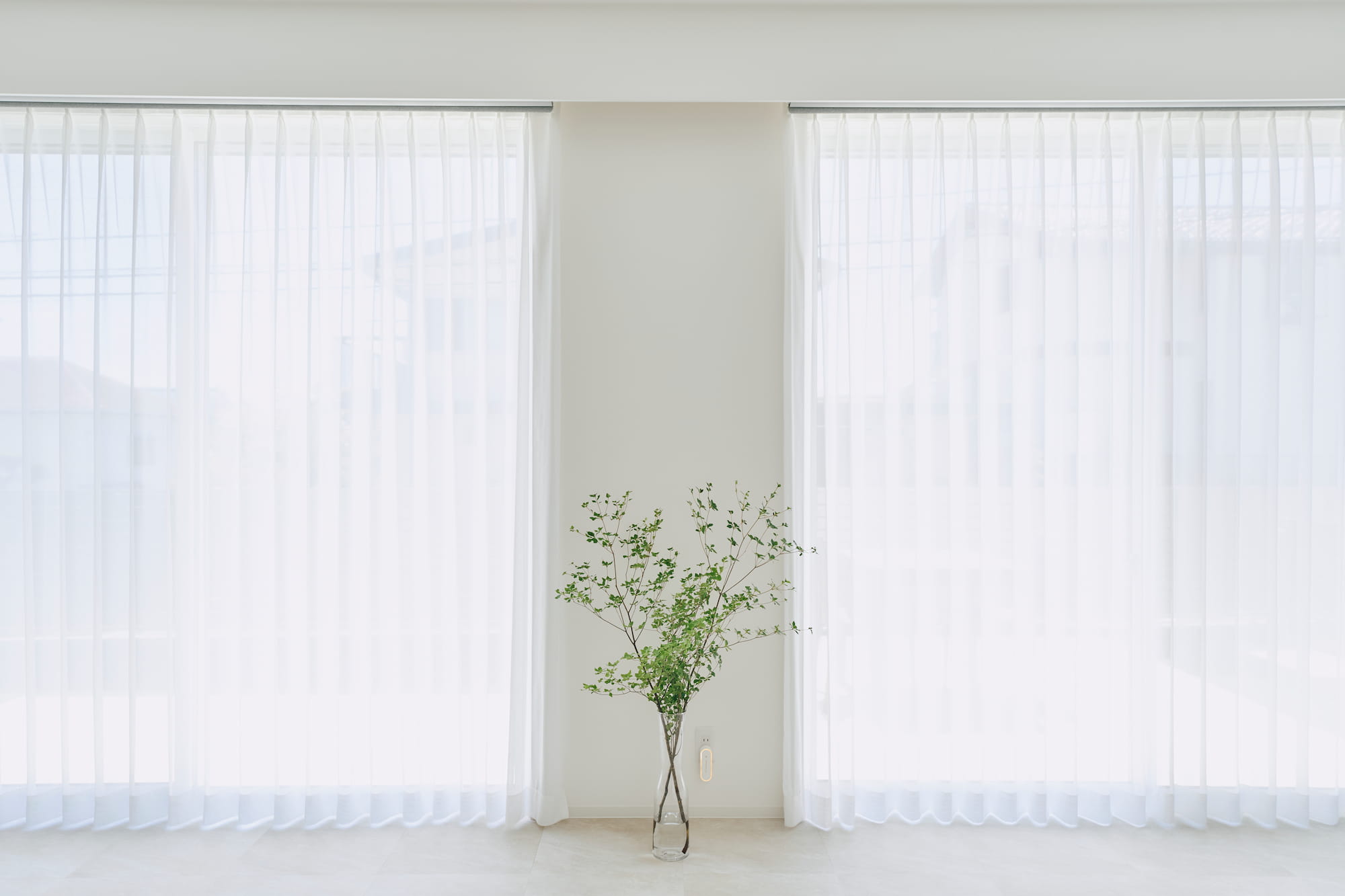 横浜の工務店による自然光を活用して心地よい日常を形にする、白い外観の住まい：カーテンを閉じた暖かな光が差し込むLDK