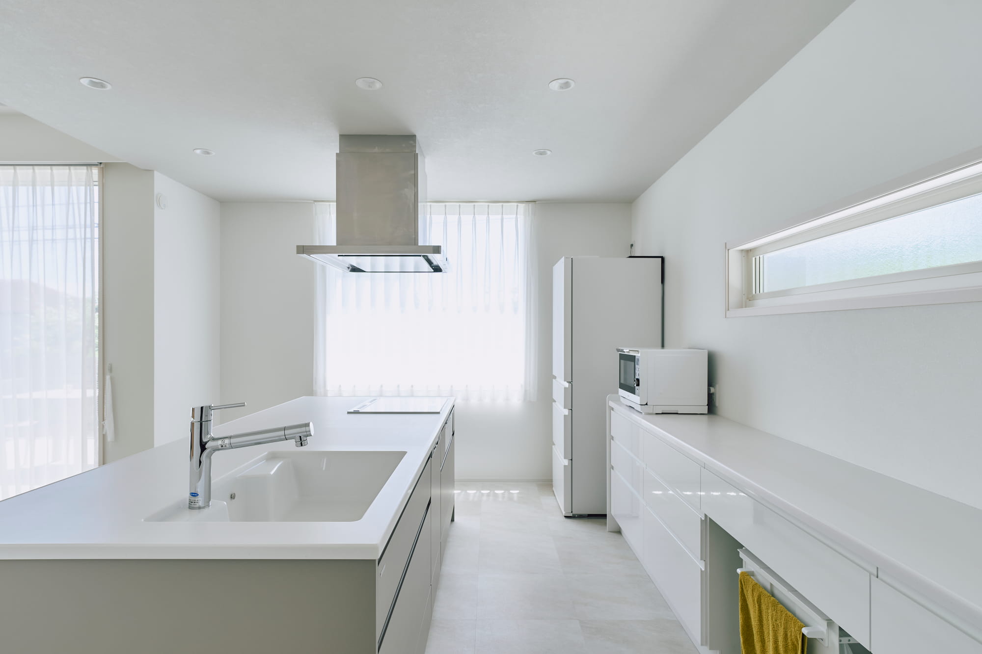 横浜の工務店による自然光を活用して心地よい日常を形にする、白い外観の住まい：明るい光に満ちた開放感のあるキッチン
