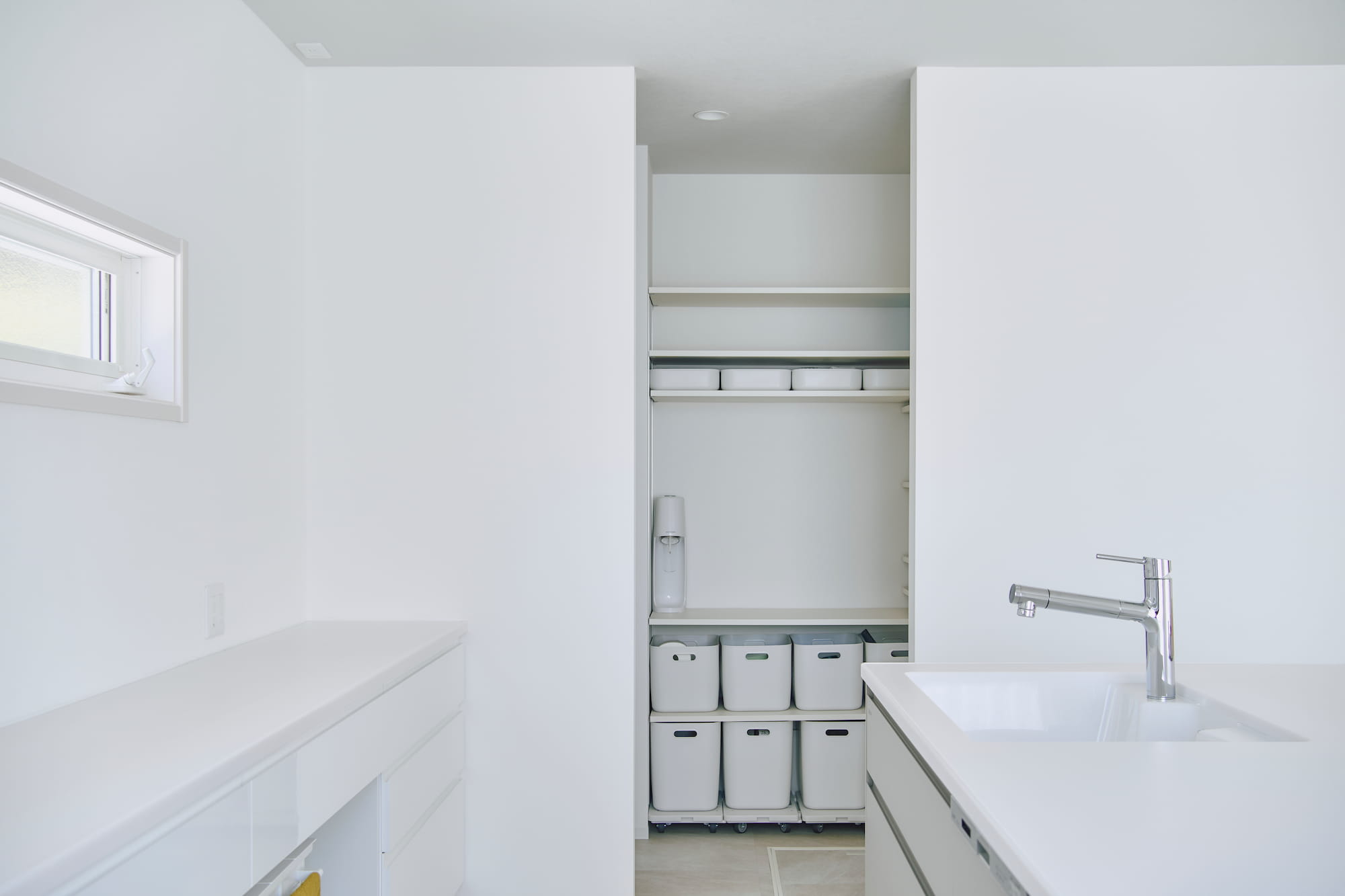 横浜の工務店による自然光を活用して心地よい日常を形にする、白い外観の住まい：統一感のある白いキッチンスペース